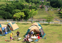 画像：キャンプ場でテントを張って食事の準備中